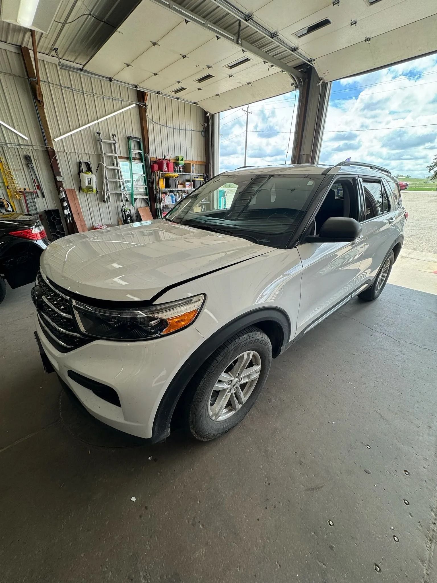 A white Ford Explorer SUV parked inside a well-lit, industrial-style garage or workshop.