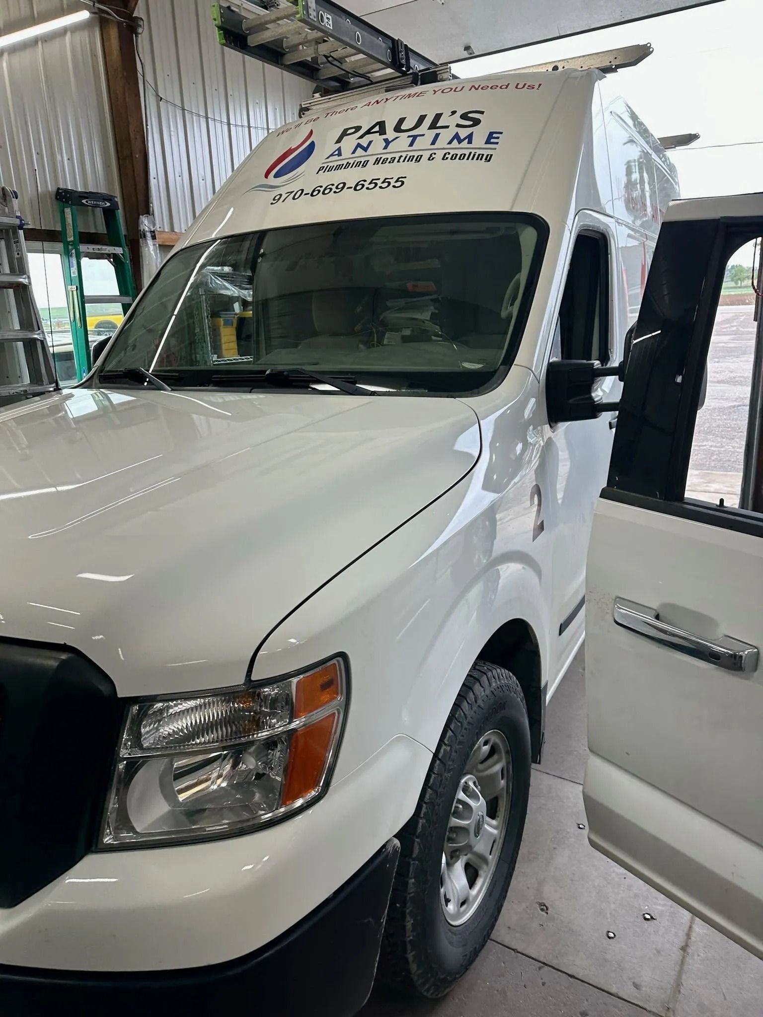 A white Paul's Anytime Electric van parked indoors with its driver-side door open.