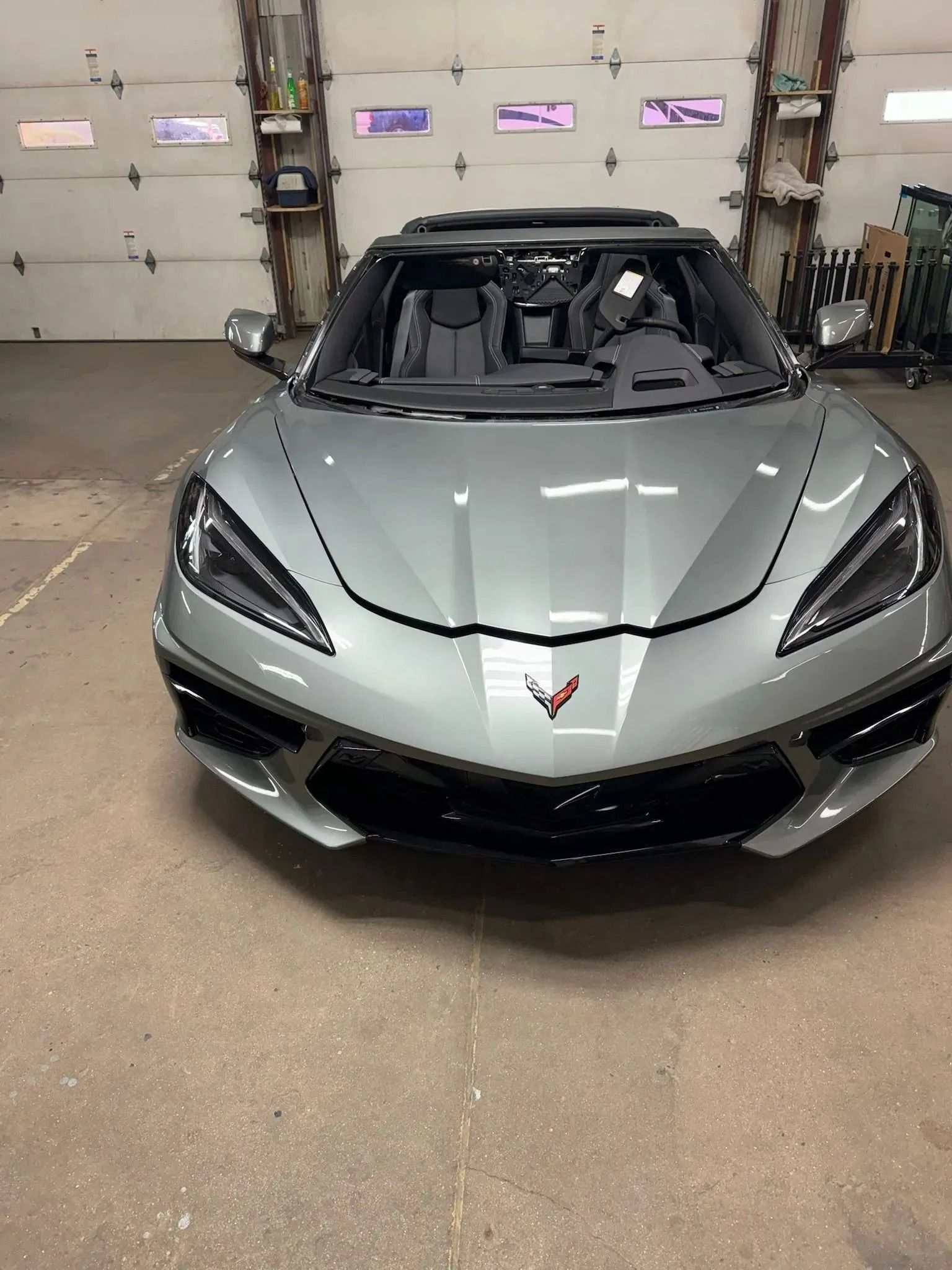 A silver Chevrolet Corvette C8 convertible parked inside a garage.
