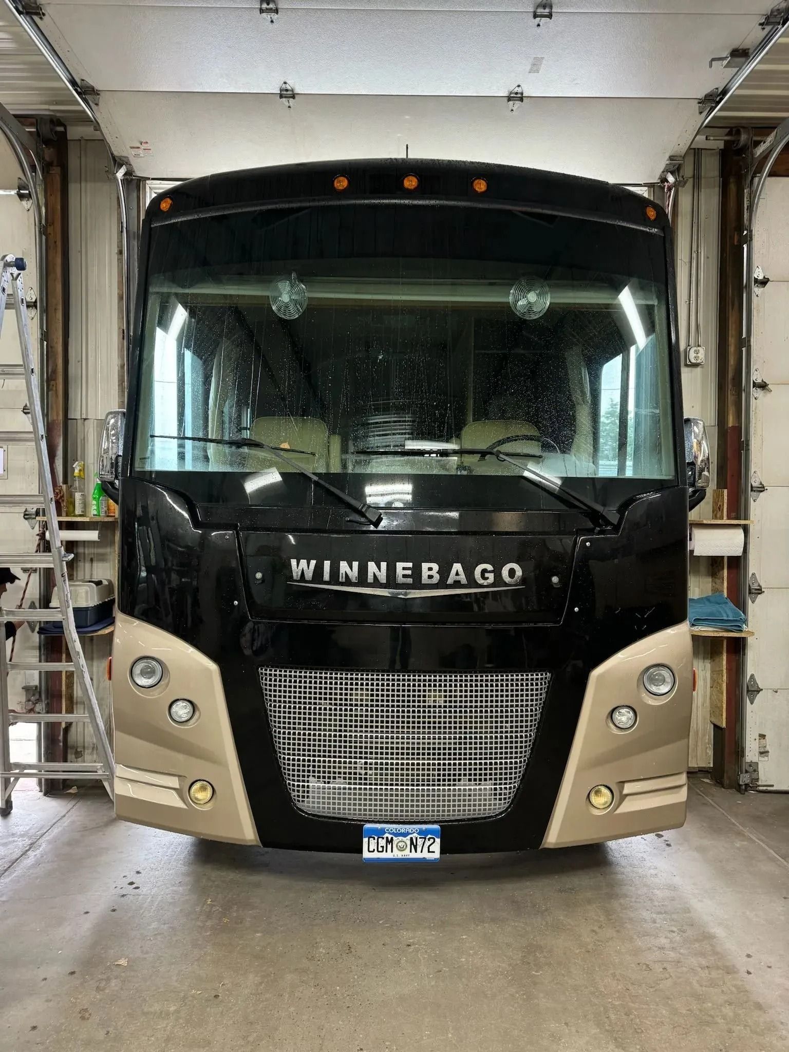 A black and beige Winnebago motorhome parked inside a garage.