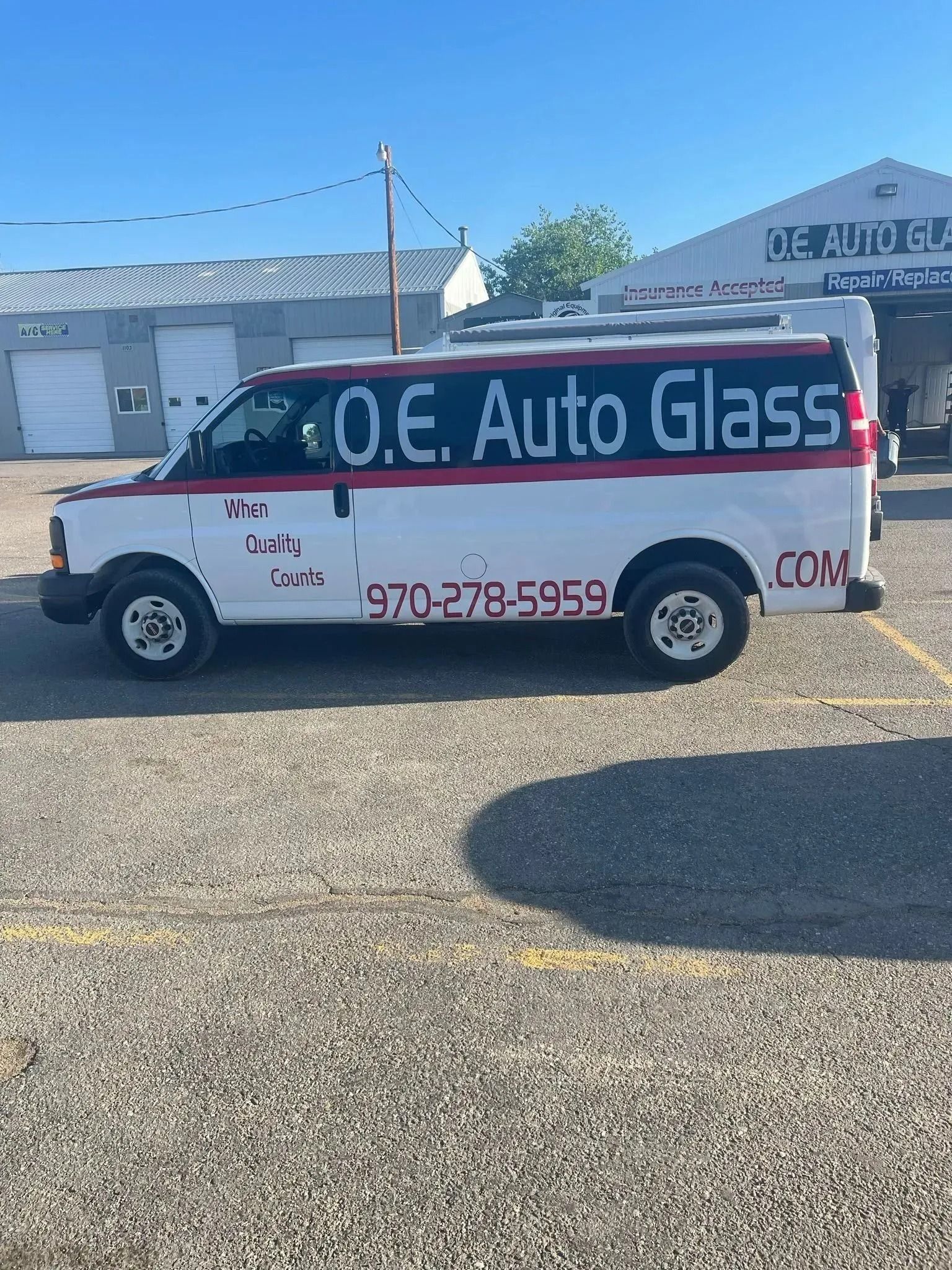 A white work van with red trim parked on gravel, marked 