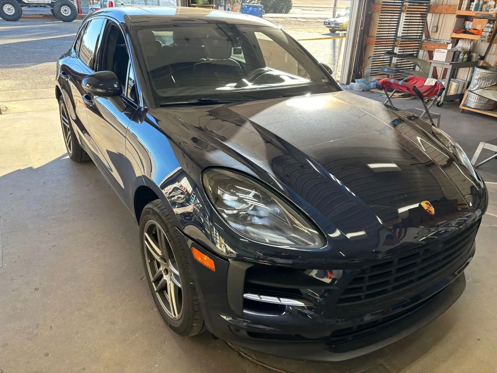 A dark blue Porsche Macan SUV parked inside a garage, angled toward the left.
