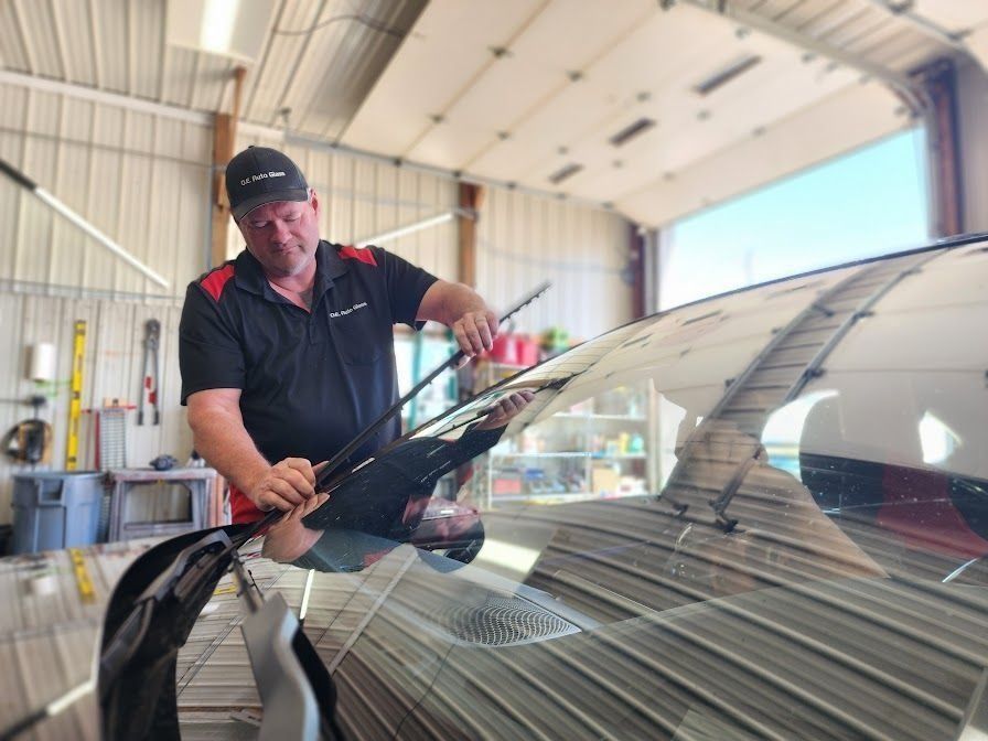 A technician in a garage workshop installs a new windshield wiper on a vehicle.