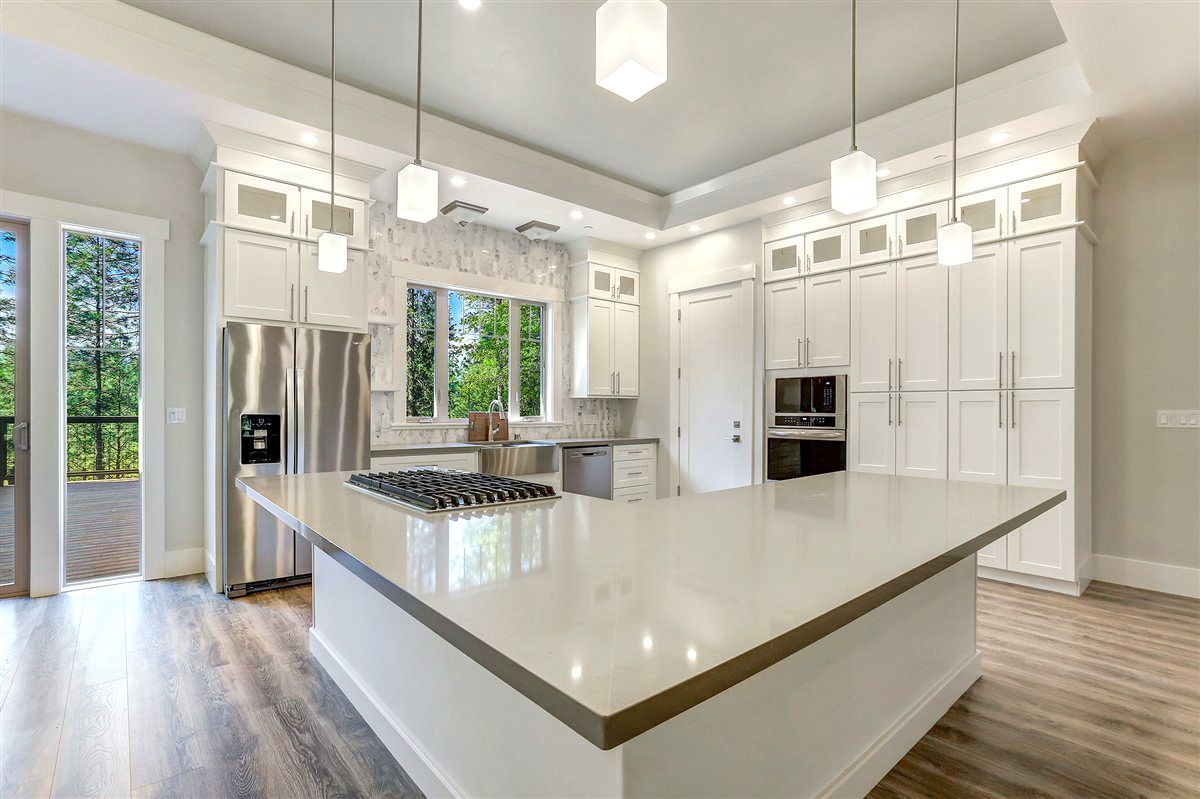 A kitchen with white cabinets , stainless steel appliances , and a large island.