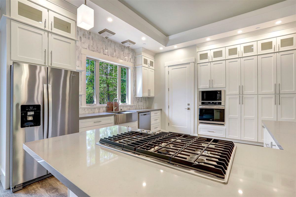A kitchen with white cabinets , stainless steel appliances , a stove top oven and a refrigerator.