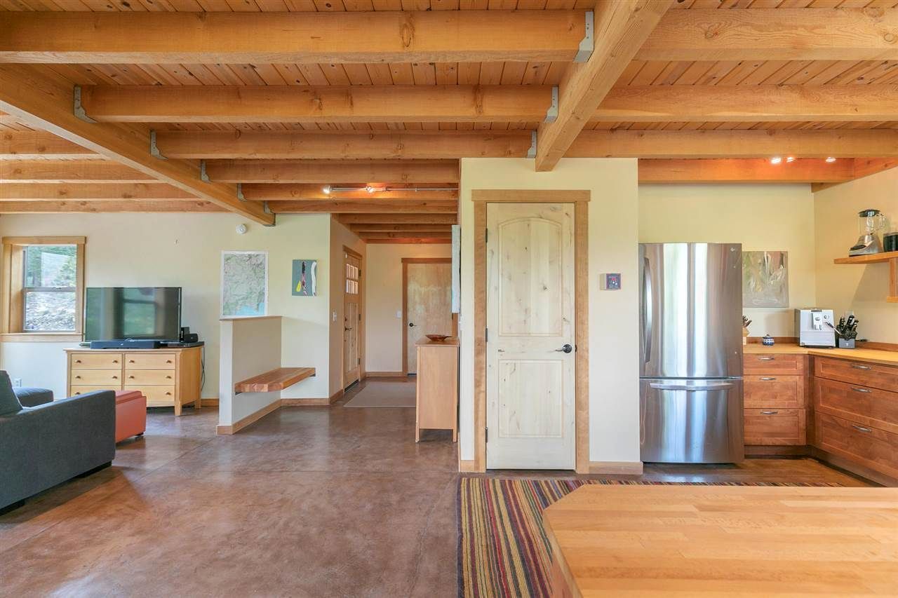 A living room and kitchen in a house with a stainless steel refrigerator.