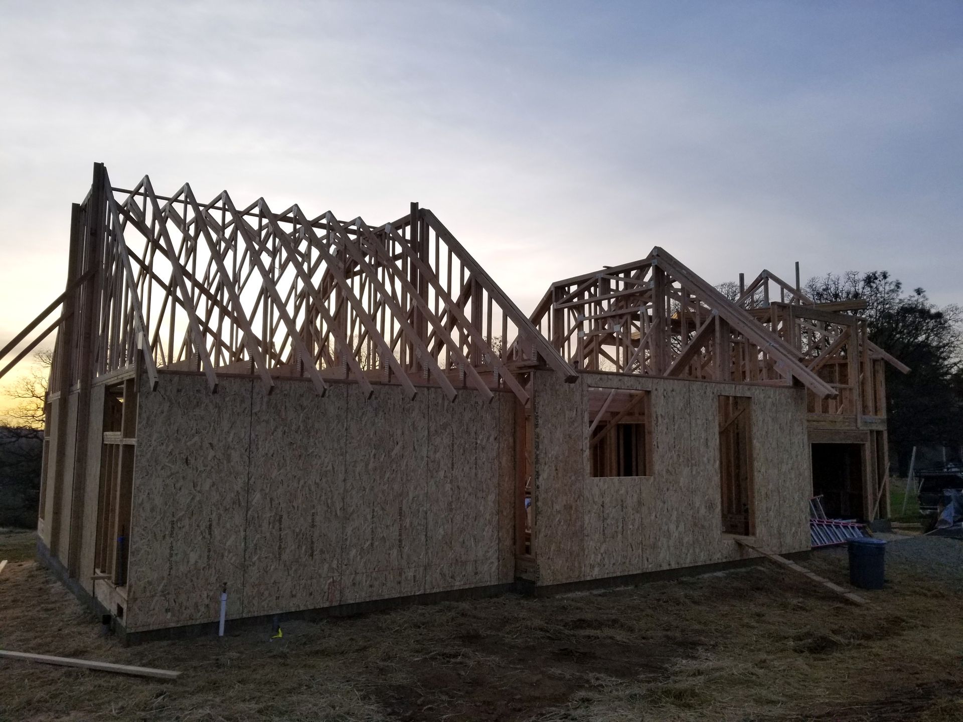 A house is being built in a field with a sunset in the background.