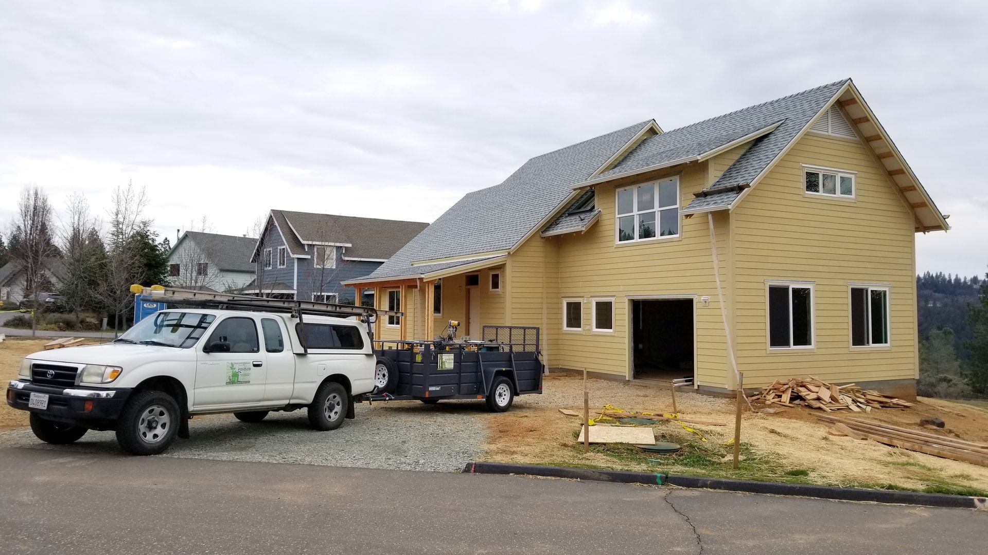A white truck is parked in front of a house under construction.