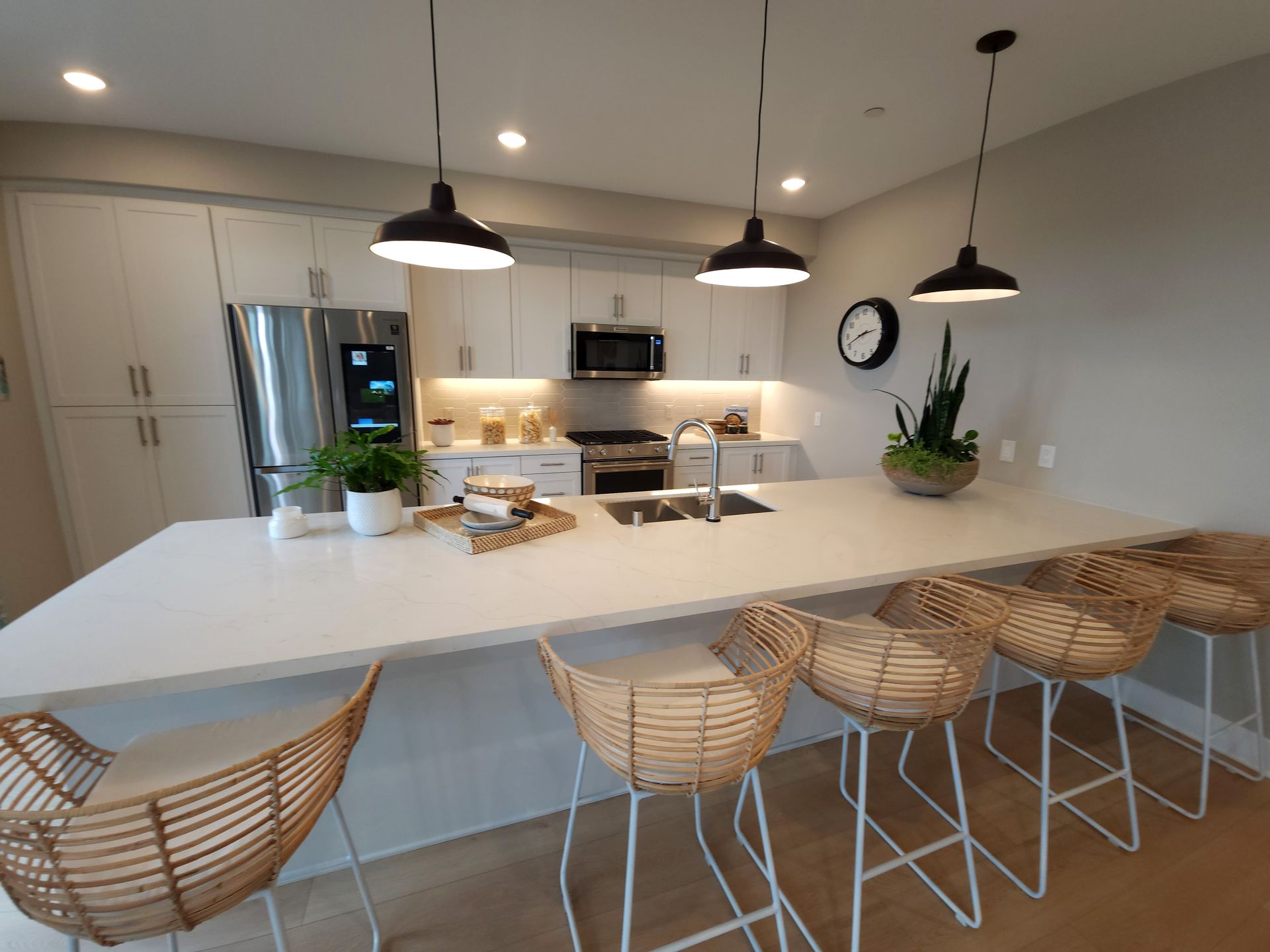 A kitchen with a large island and wicker chairs.