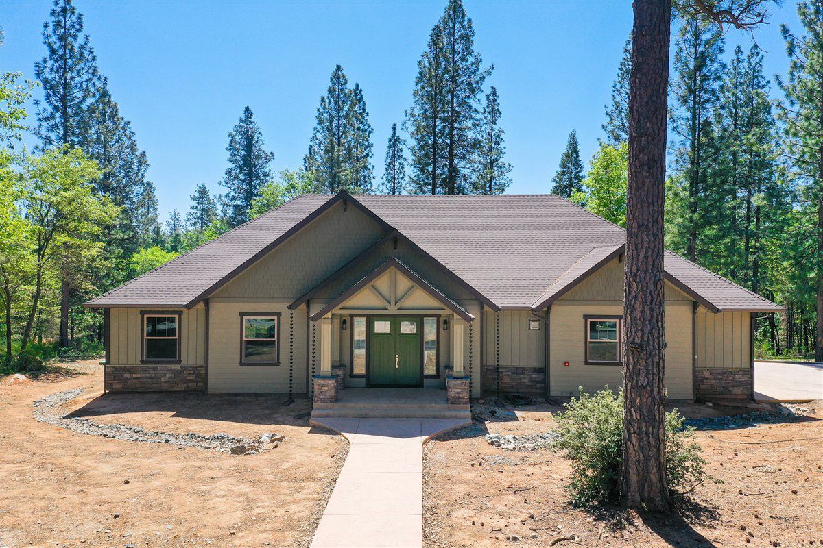 A house with a walkway leading to it is surrounded by trees.
