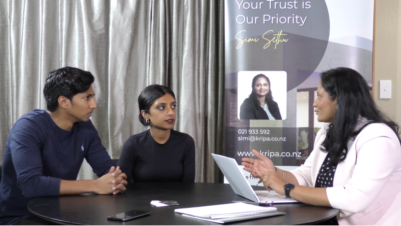 A man and a woman are sitting at a table talking to a woman.