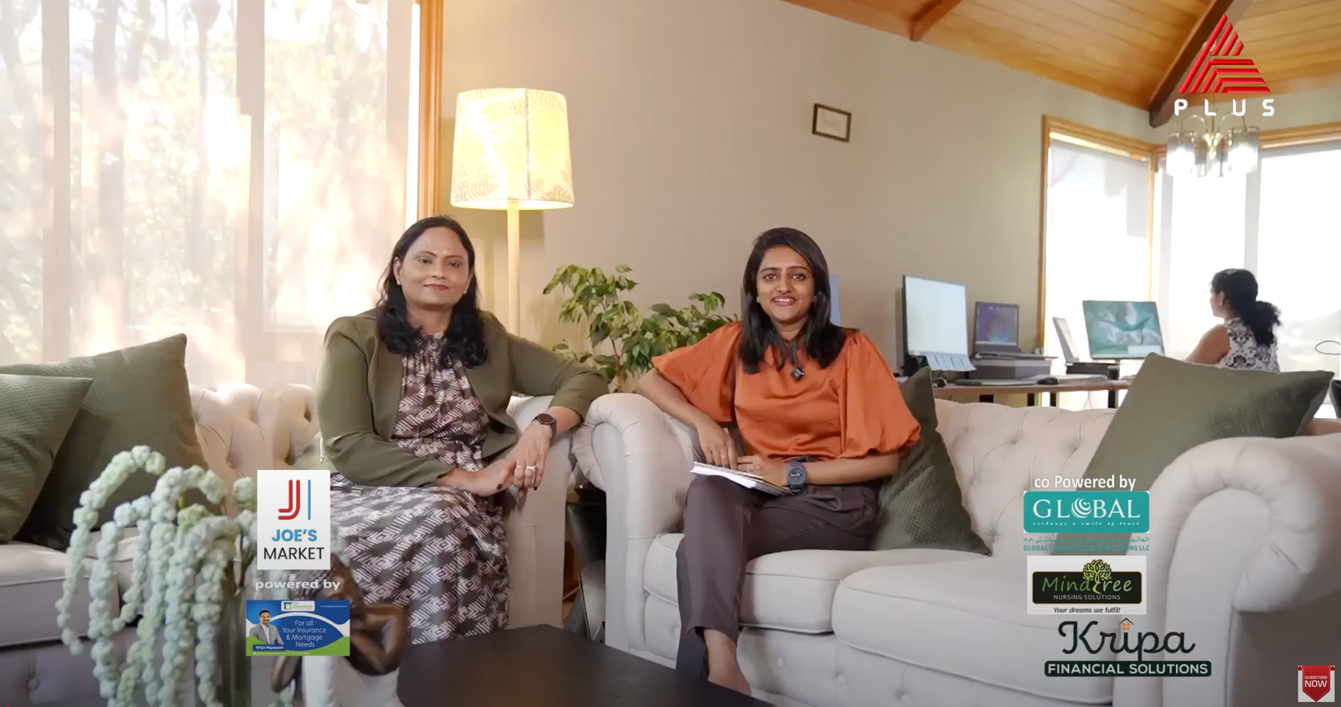 Two women are sitting on a couch in a living room.
