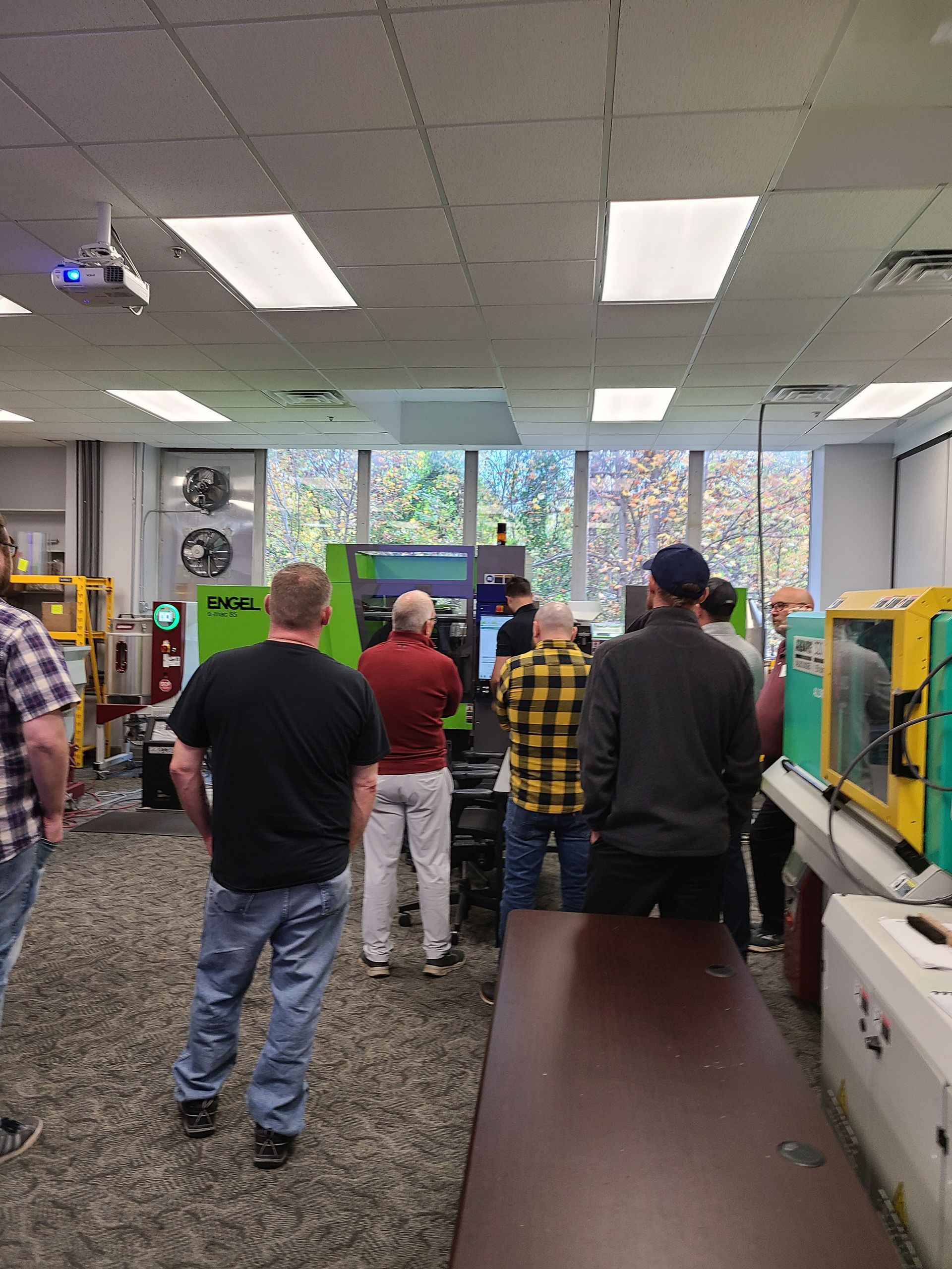 A group of men are standing in a room looking at a machine.