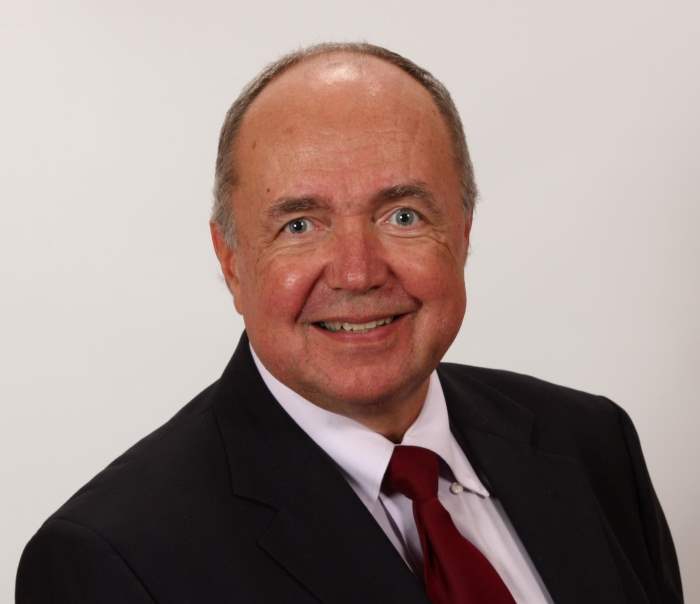 A man in a suit and tie is smiling for the camera