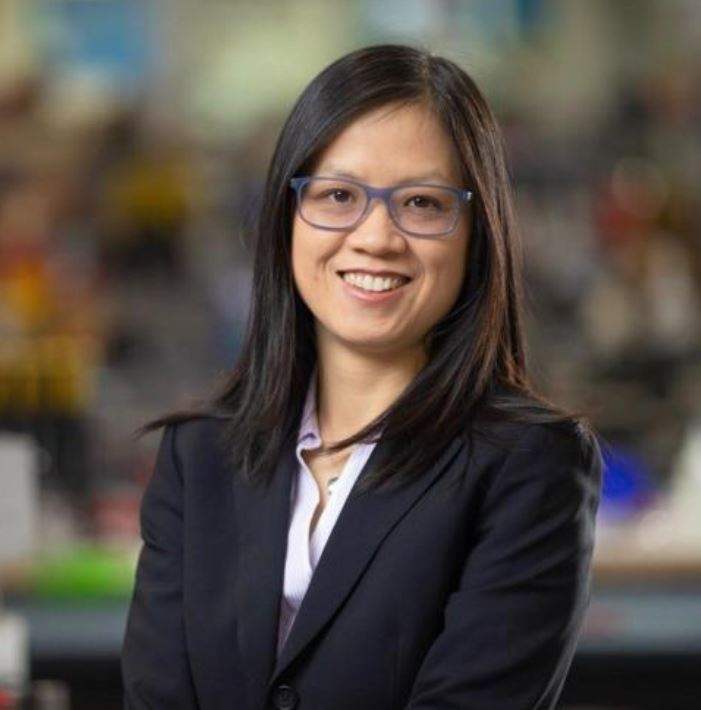 A woman wearing glasses and a suit is smiling for the camera.