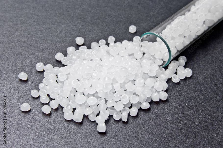 A glass tube filled with white plastic granules on a table.