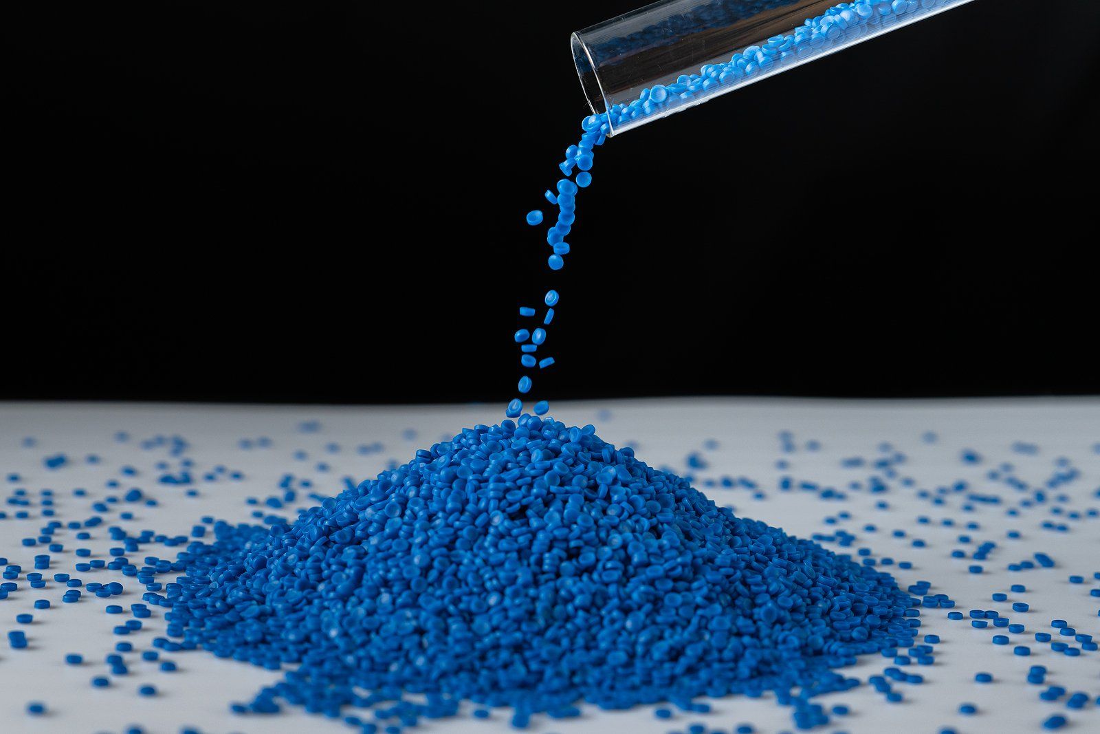 blue plastic granules are being poured into a pile on a table 