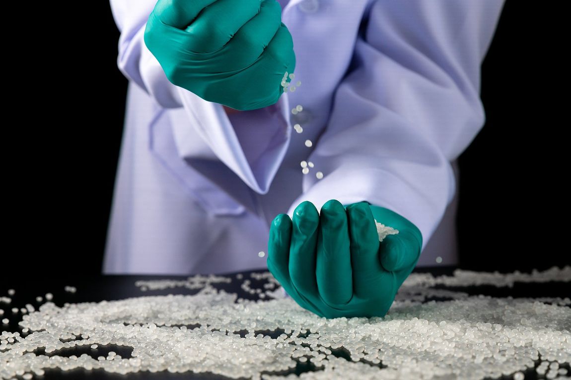 A person wearing green gloves is spreading salt on a table.