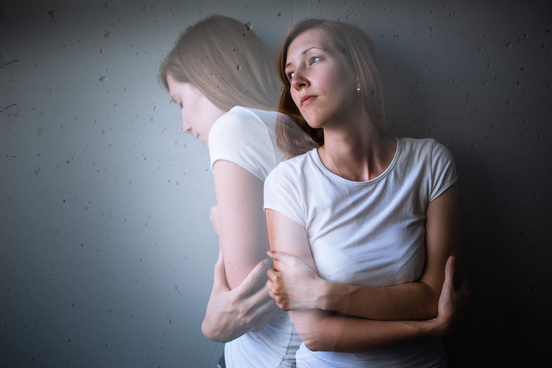 a woman in a white shirt is hugging herself