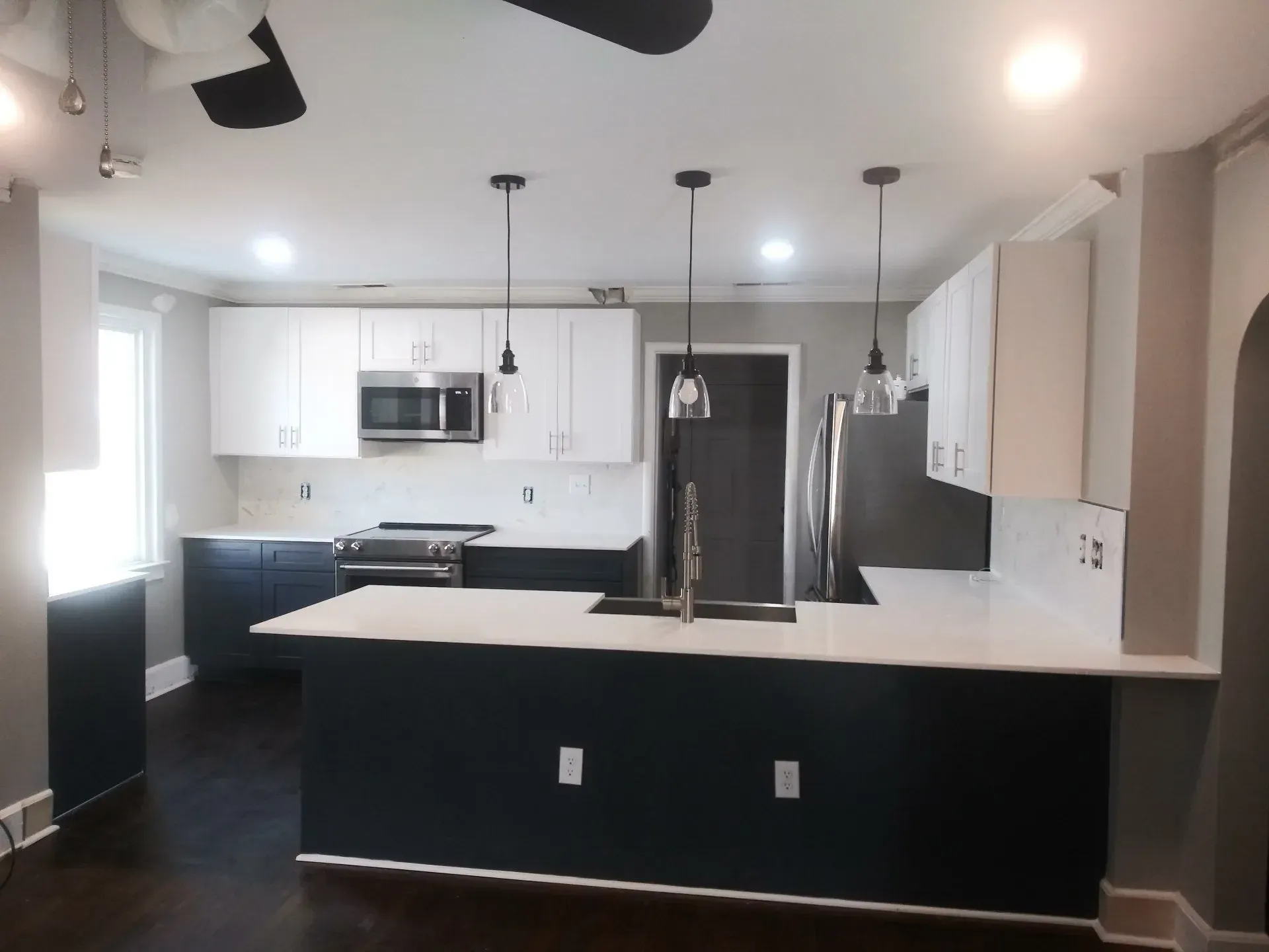 Modern kitchen with white upper cabinets, dark blue lower cabinets, and a white countertop island.