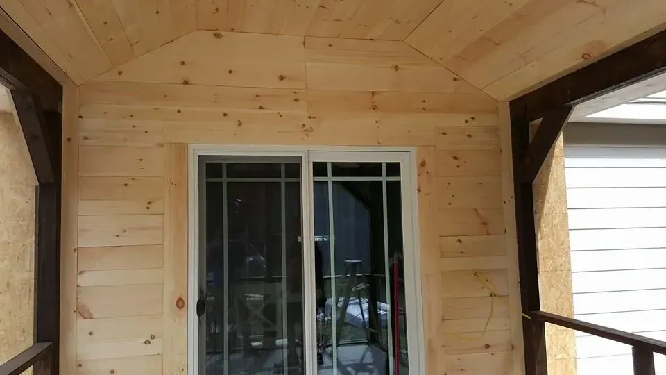 Wooden porch with sliding glass door and dark brown trim.