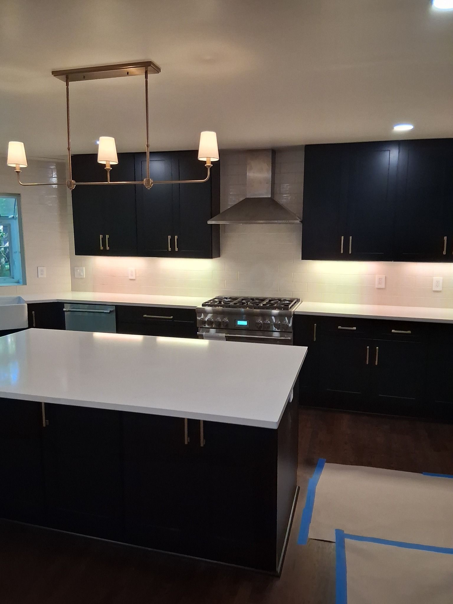 Modern kitchen with navy blue cabinets, white countertops, and gold hardware.