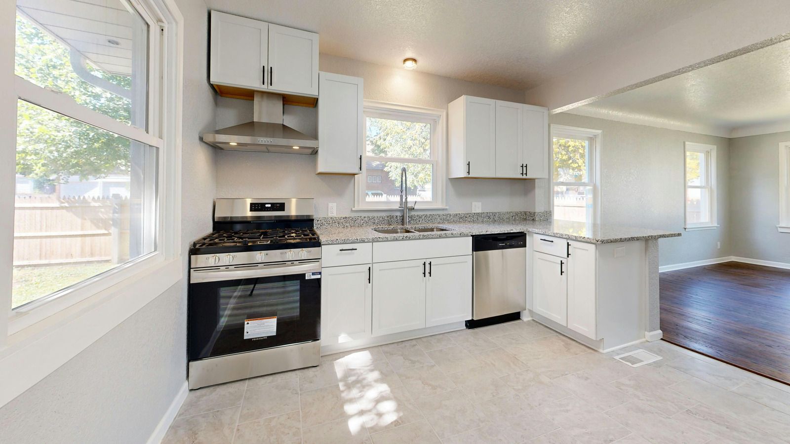 Modern kitchen with white cabinets, stainless steel appliances, and large windows.