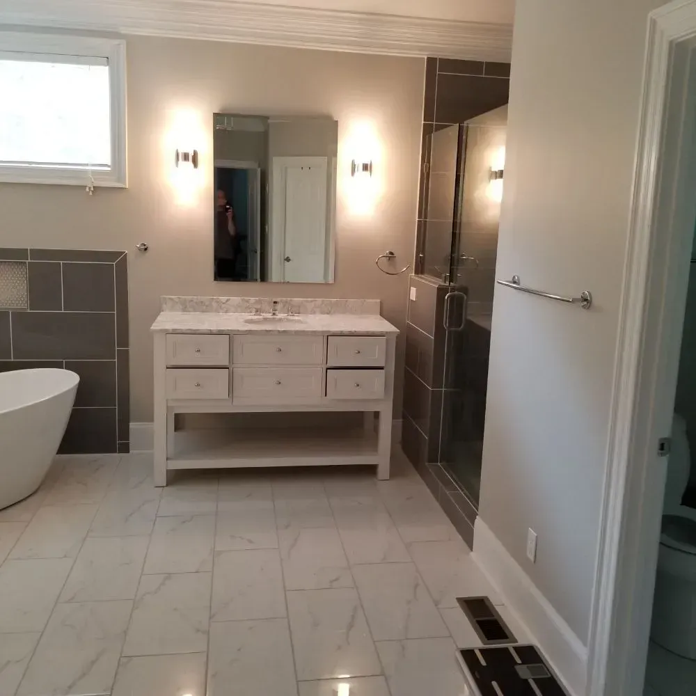 Modern bathroom with white vanity, gray shower, soaking tub, and marble floors.
