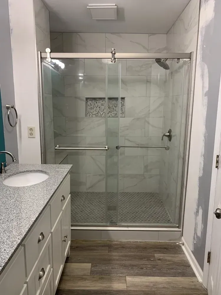 Bathroom with a glass shower, marble tile, and a vanity with a granite countertop and a round sink.