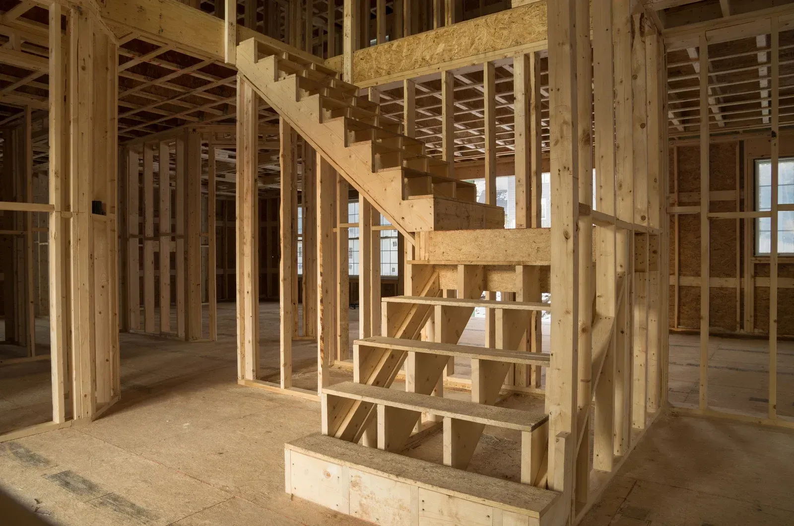 Interior view of a wooden framed house under construction with a staircase.