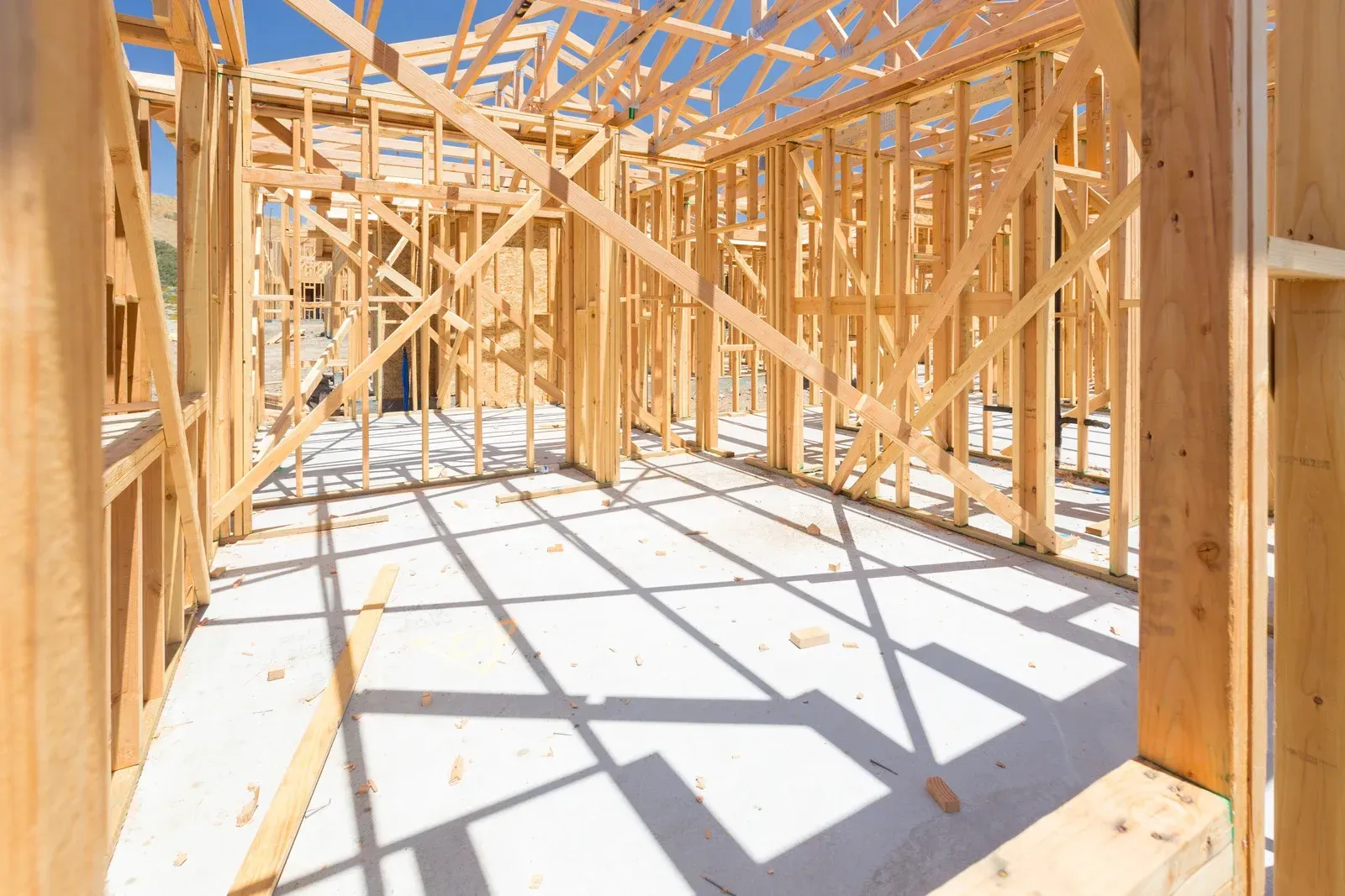 Wooden frame of a building under construction, shadows on a concrete floor.