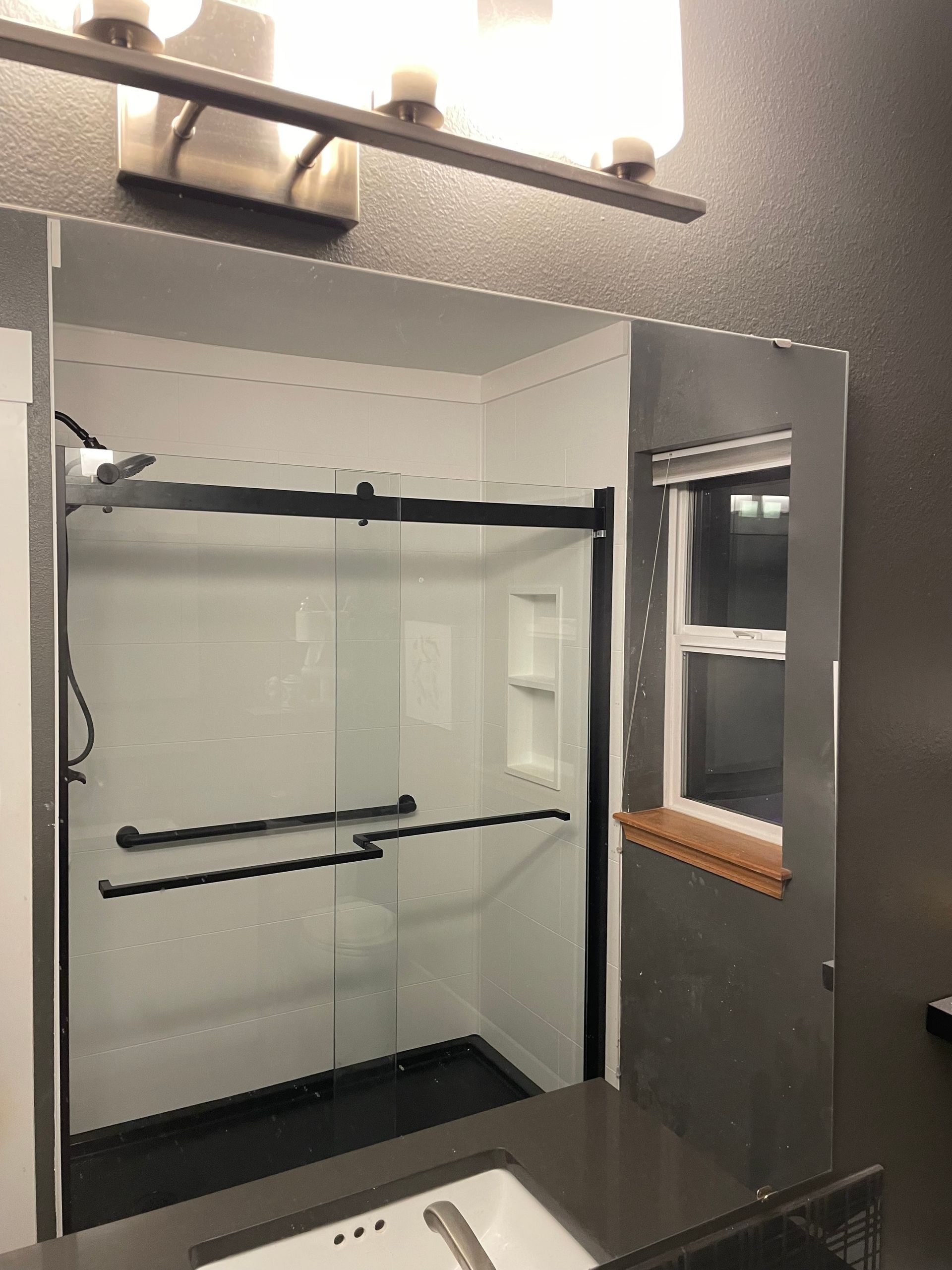 Bathroom with a white shower, black fixtures, and small window.