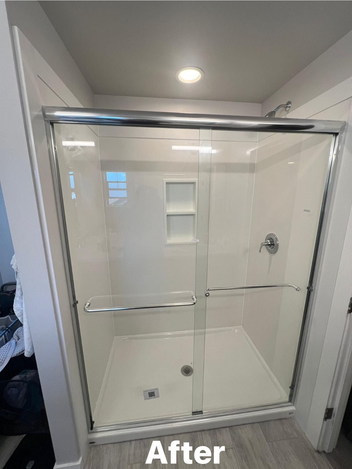 White and chrome shower with sliding glass doors and built-in shelf, labeled 