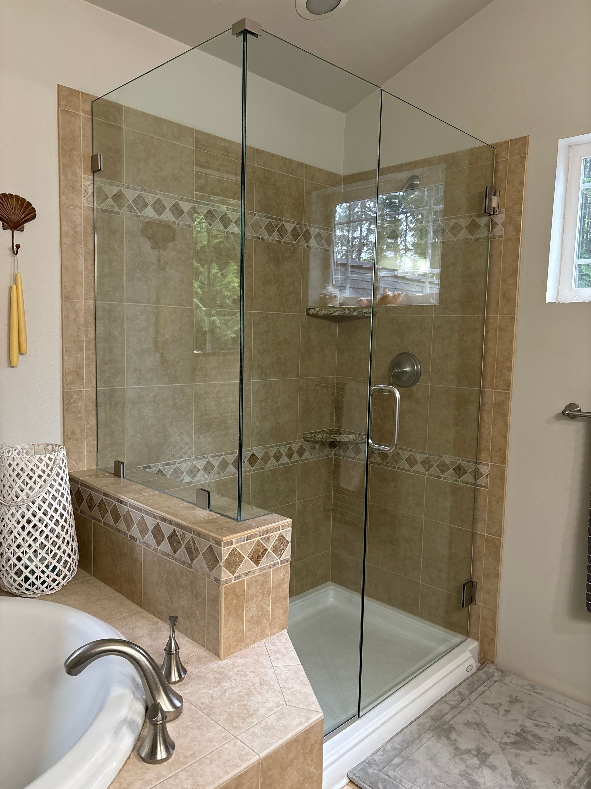 A glass-enclosed shower with tan tile, a small window, and a white shower base in a bathroom.
