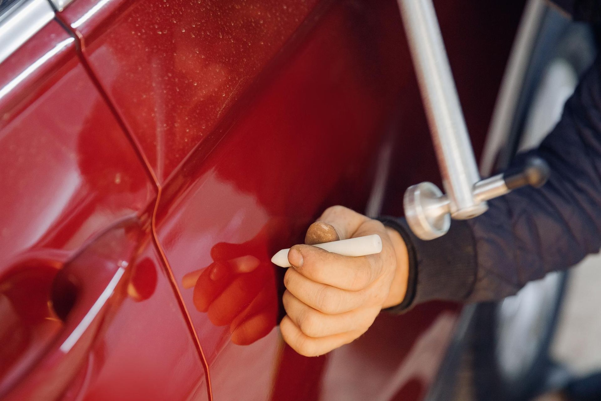 Hand polishing a red car door with a cloth