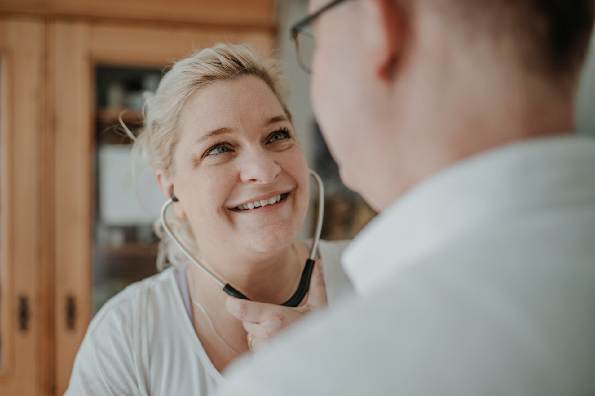 Eine Frau lächelt und trägt ein Stethoskop um den Hals.