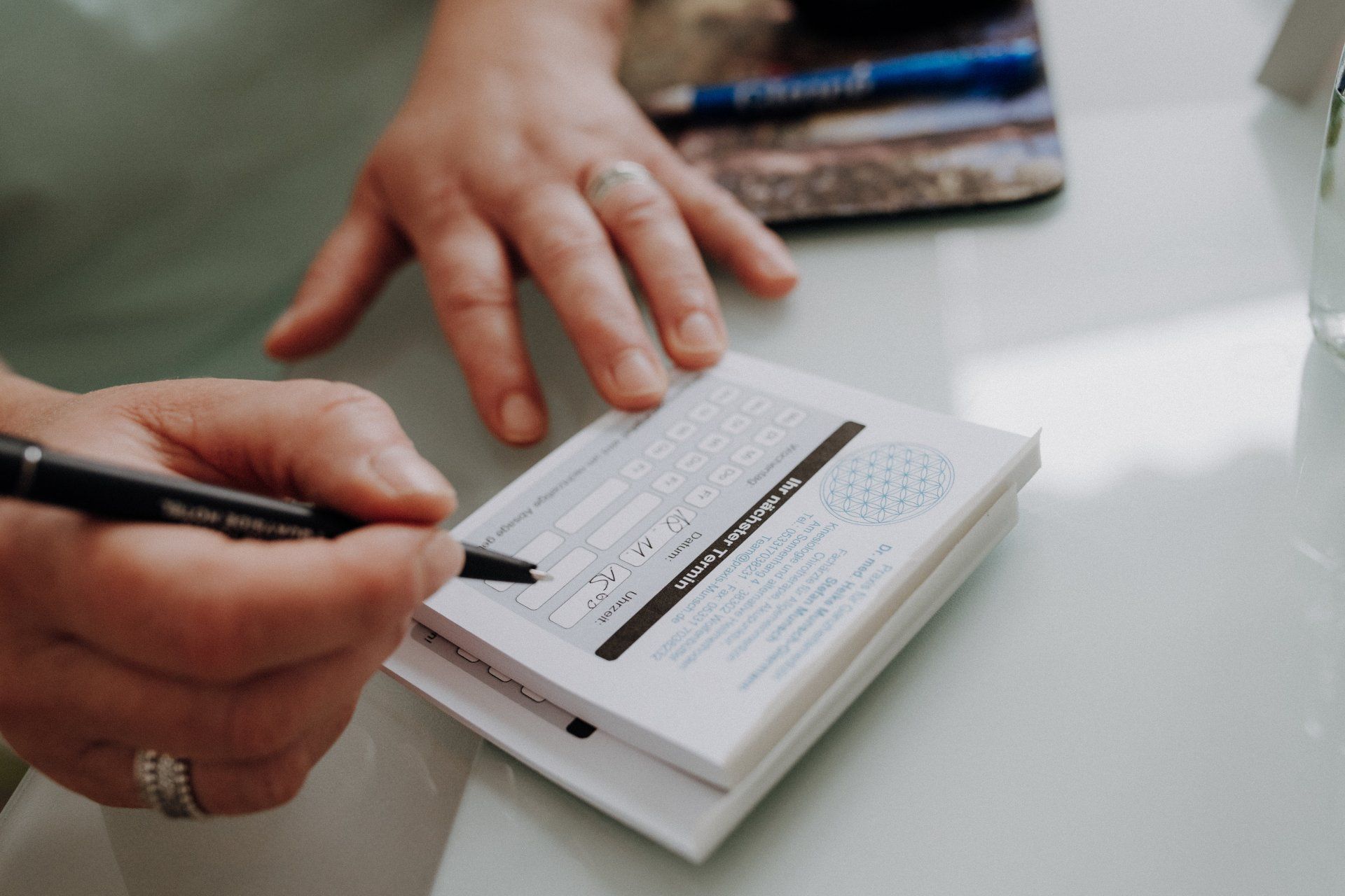 Eine Person schreibt mit einem Stift auf ein Blatt Papier.