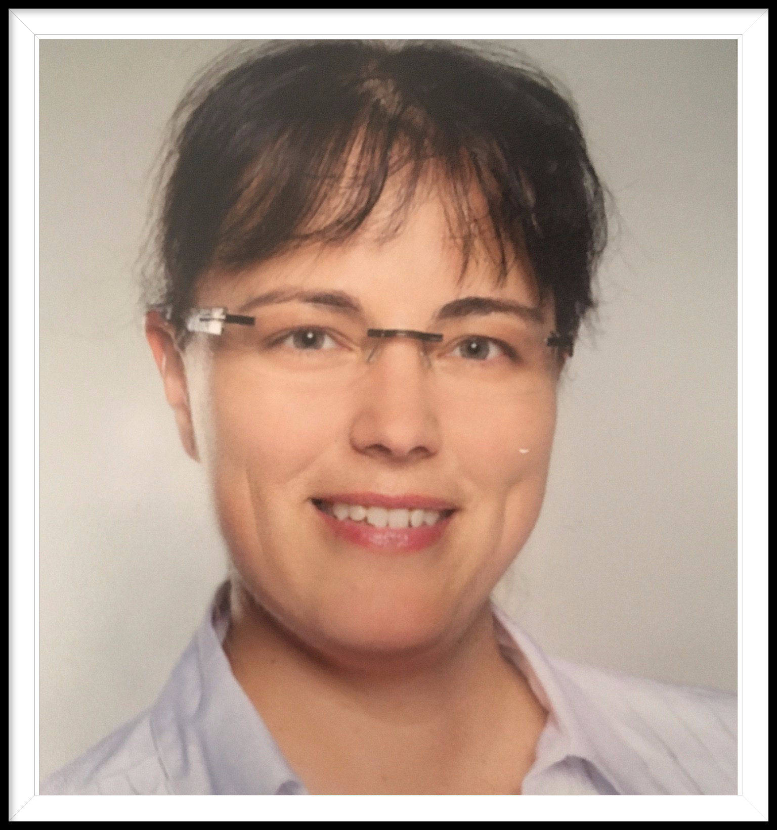 Eine Frau mit Brille und weißem Hemd lächelt in die Kamera