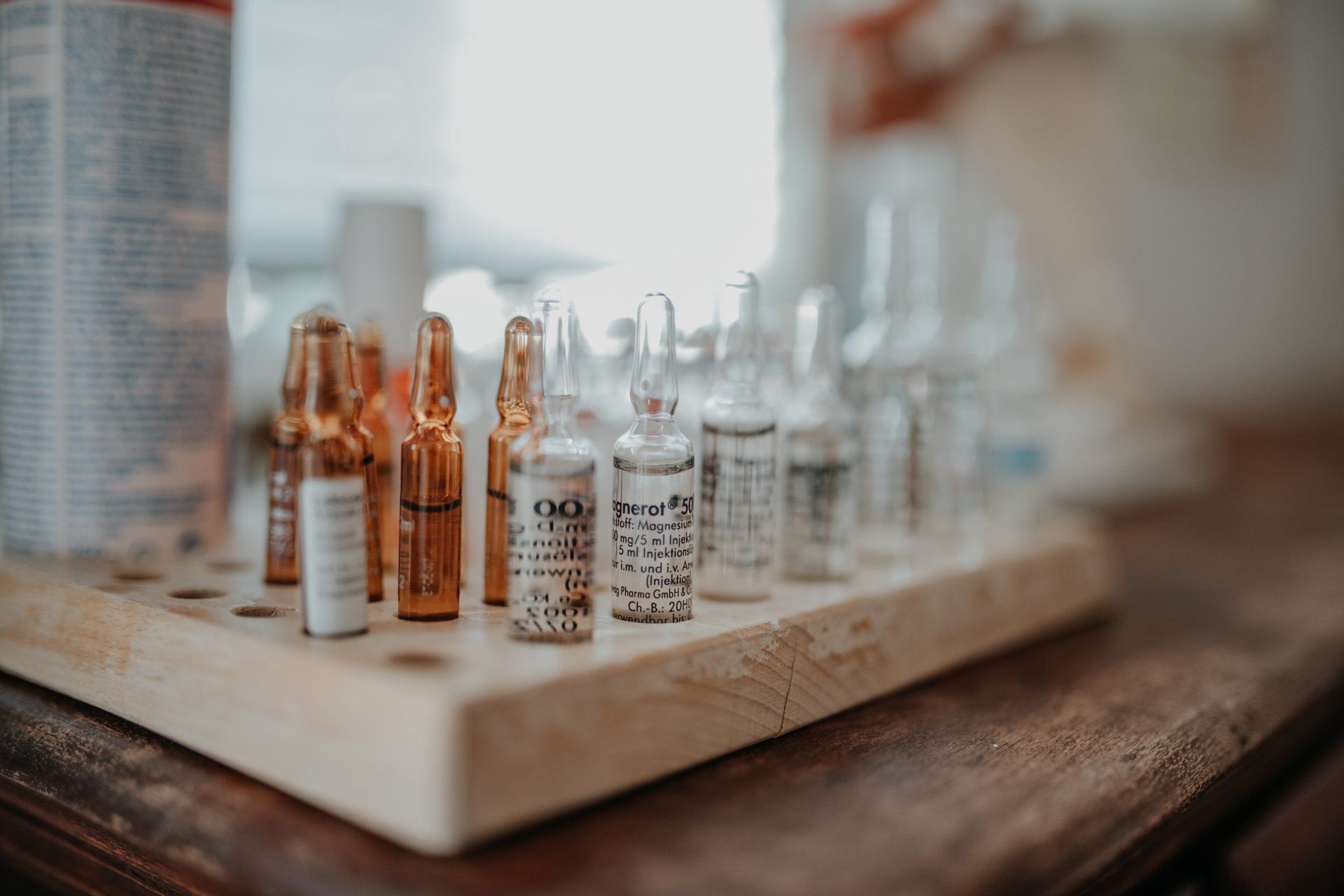 Ein Holztablett voller Medikamentenflaschen auf einem Holztisch.