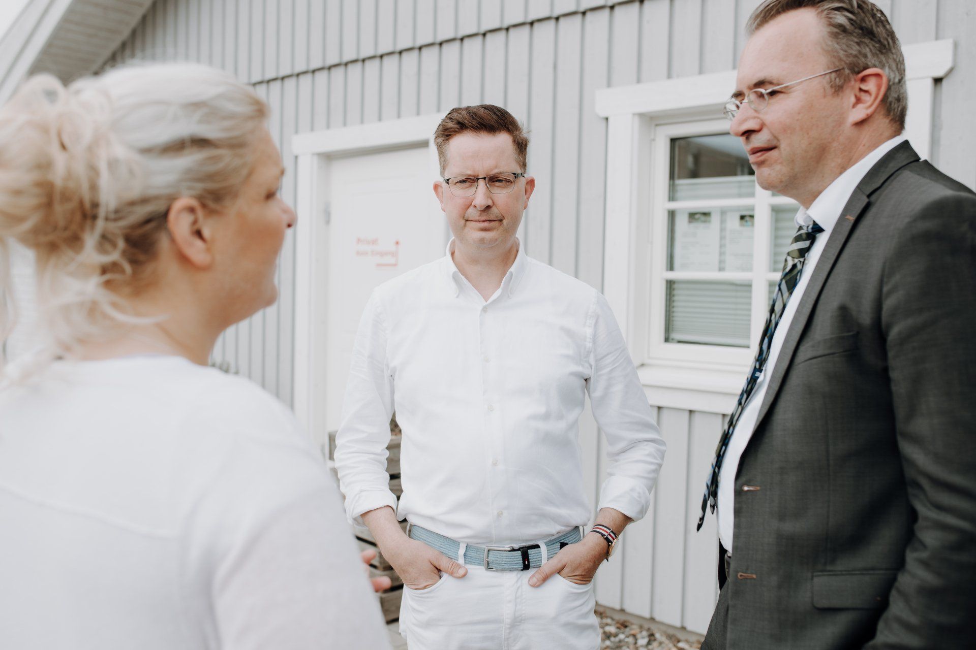 Eine Gruppe von Menschen steht vor einem Gebäude und unterhält sich.