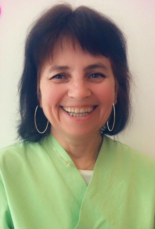 Eine Frau in einem grünen Hemd und Creolen lächelt in die Kamera.