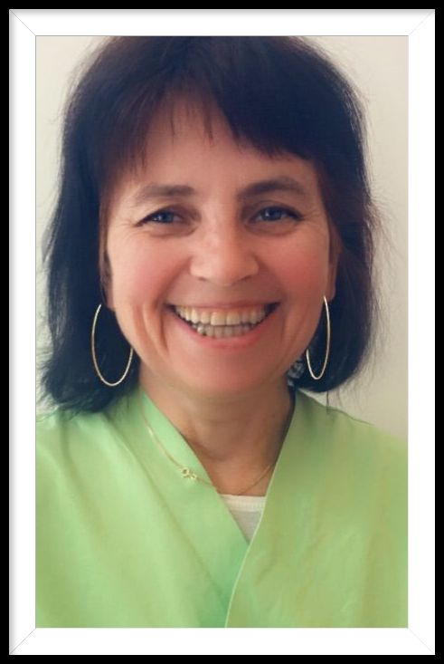 Eine Frau in einem grünen Hemd und Creolen lächelt in die Kamera.