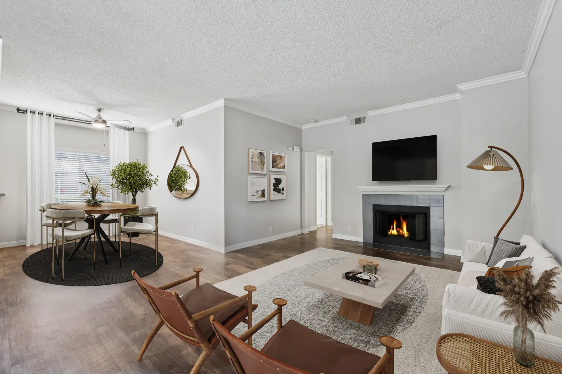 Open-concept living room with a fireplace, TV above a mantel, white sofa, and round dining table.