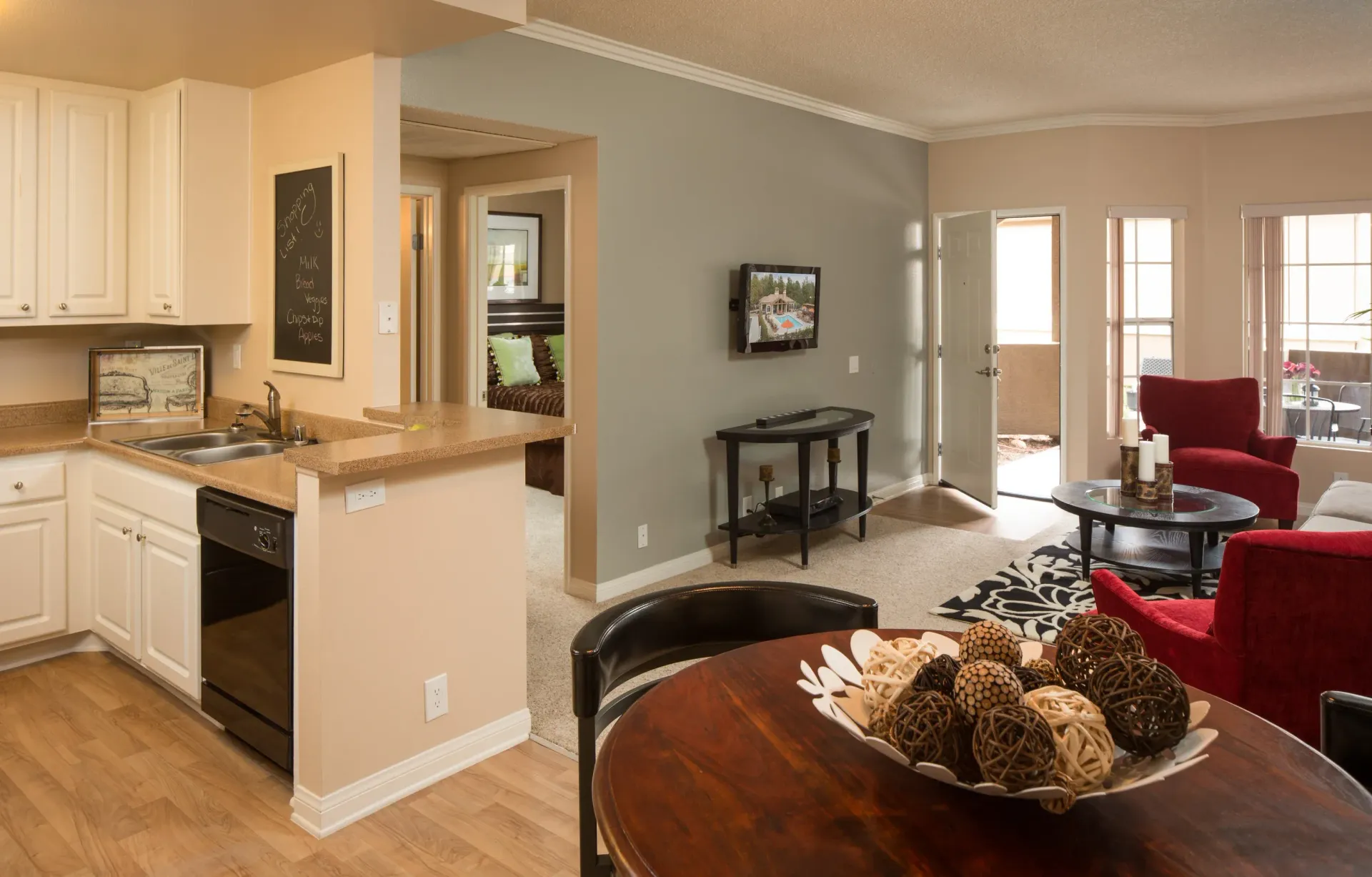 Open-concept apartment living area with kitchen on the left and a patio door.