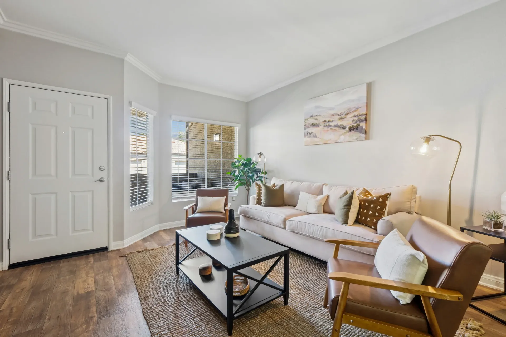 Bright living room with beige sofa, two chairs, coffee table, and large windows.