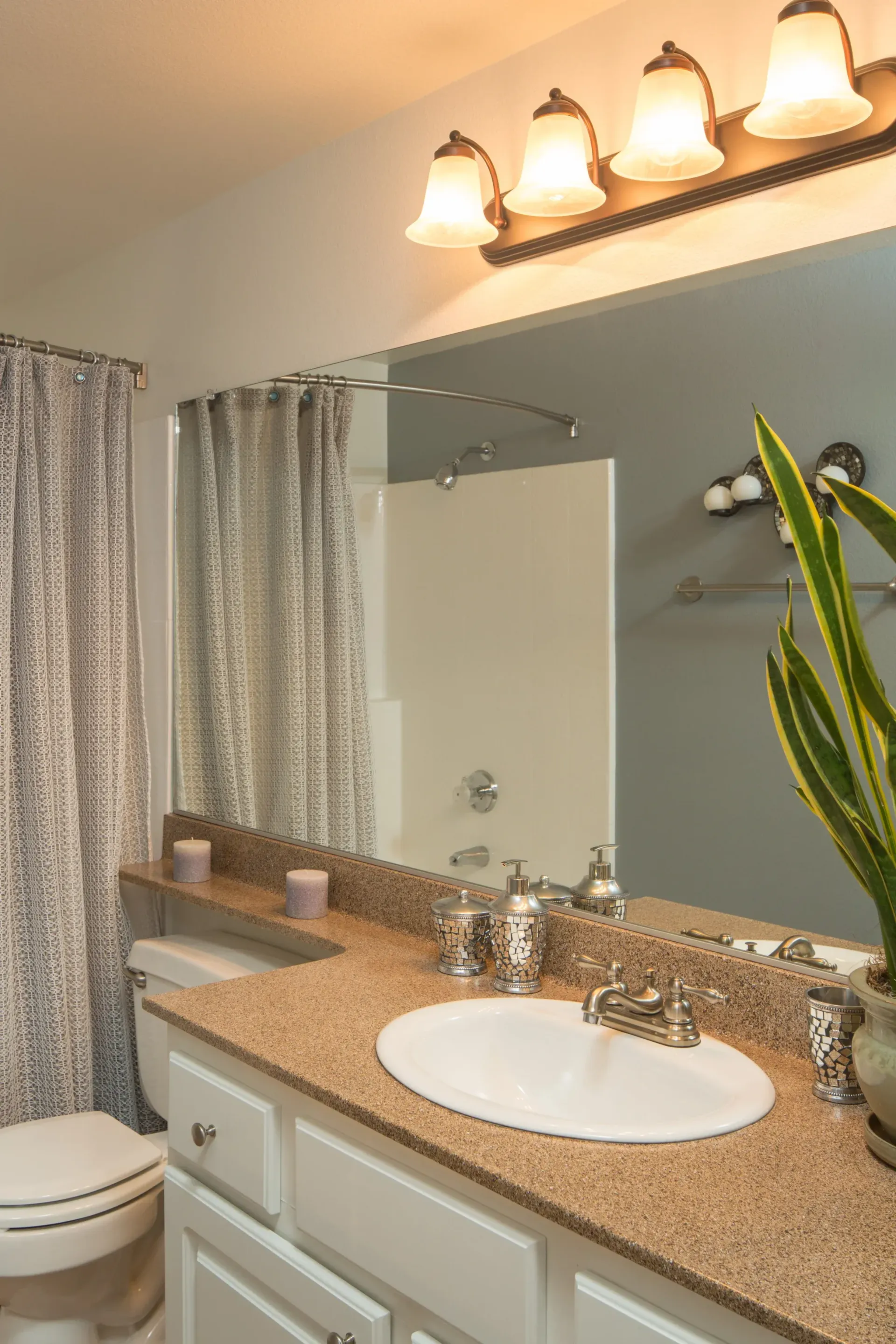 Bathroom vanity with sink, large mirror, beige granite countertop, and shower curtain.