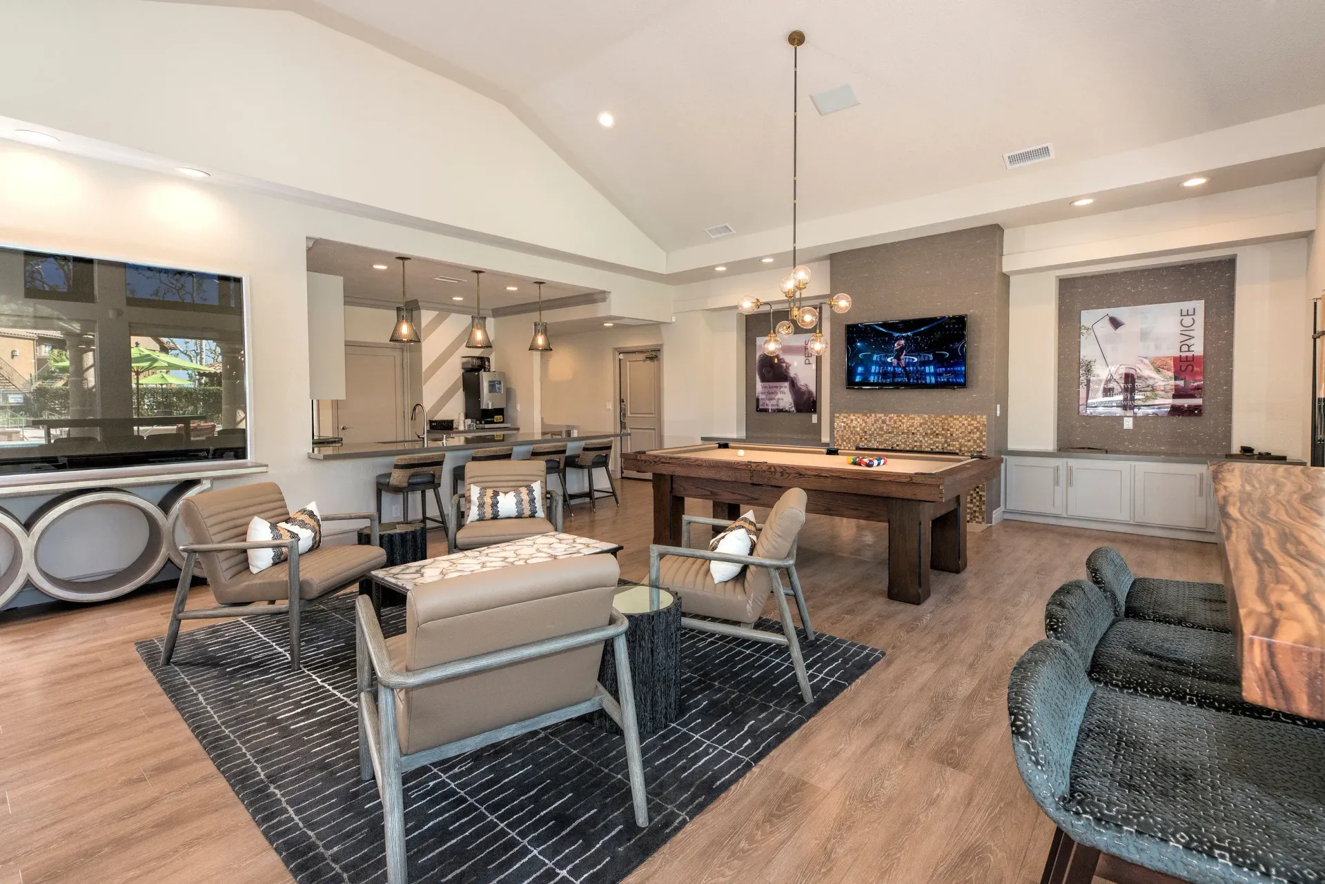 Modern communal lounge with a pool table, bar seating, and a wall-mounted TV.