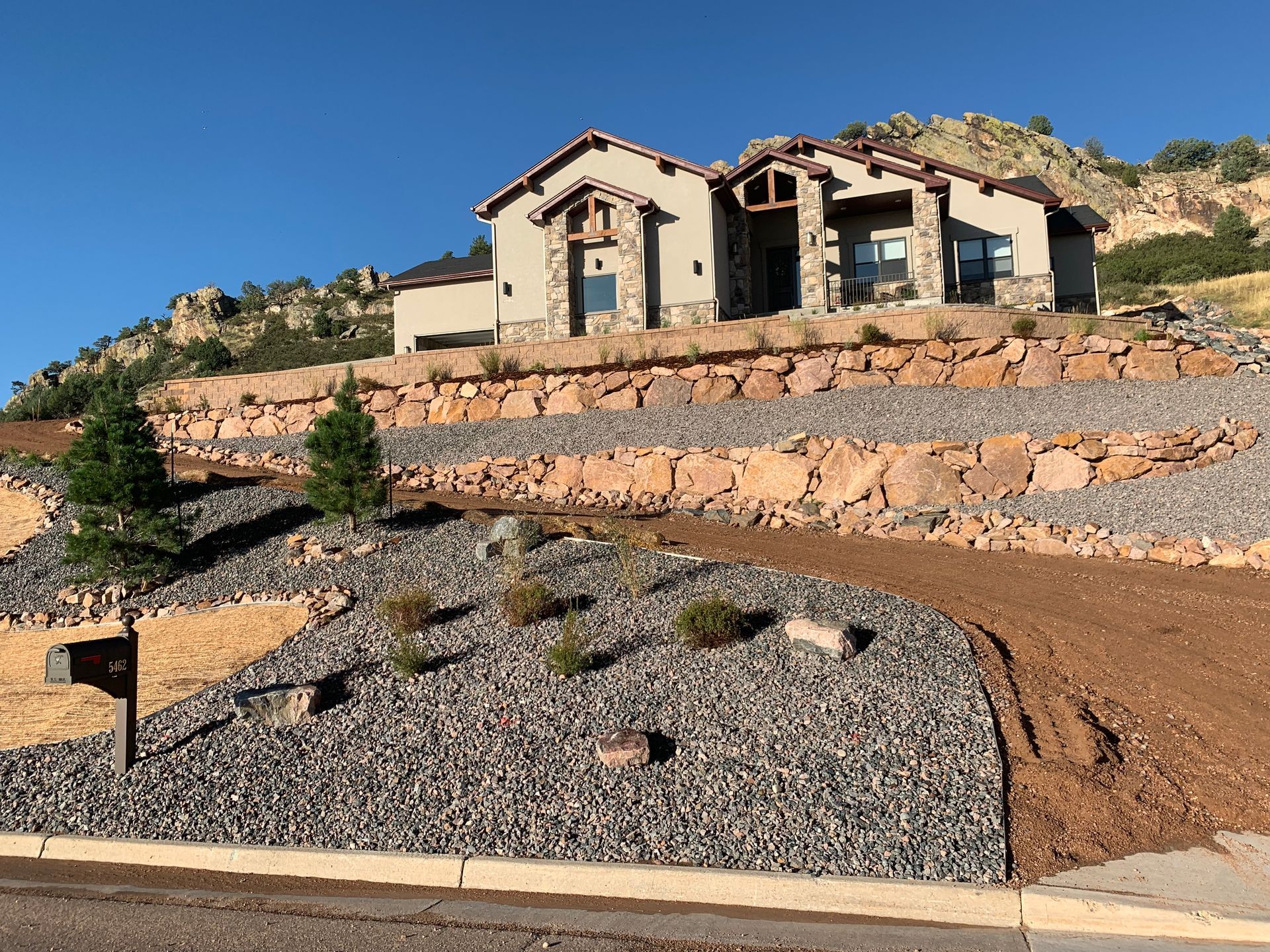 Covered patio with seating, plants, and mountain view, with a pool and lawn.