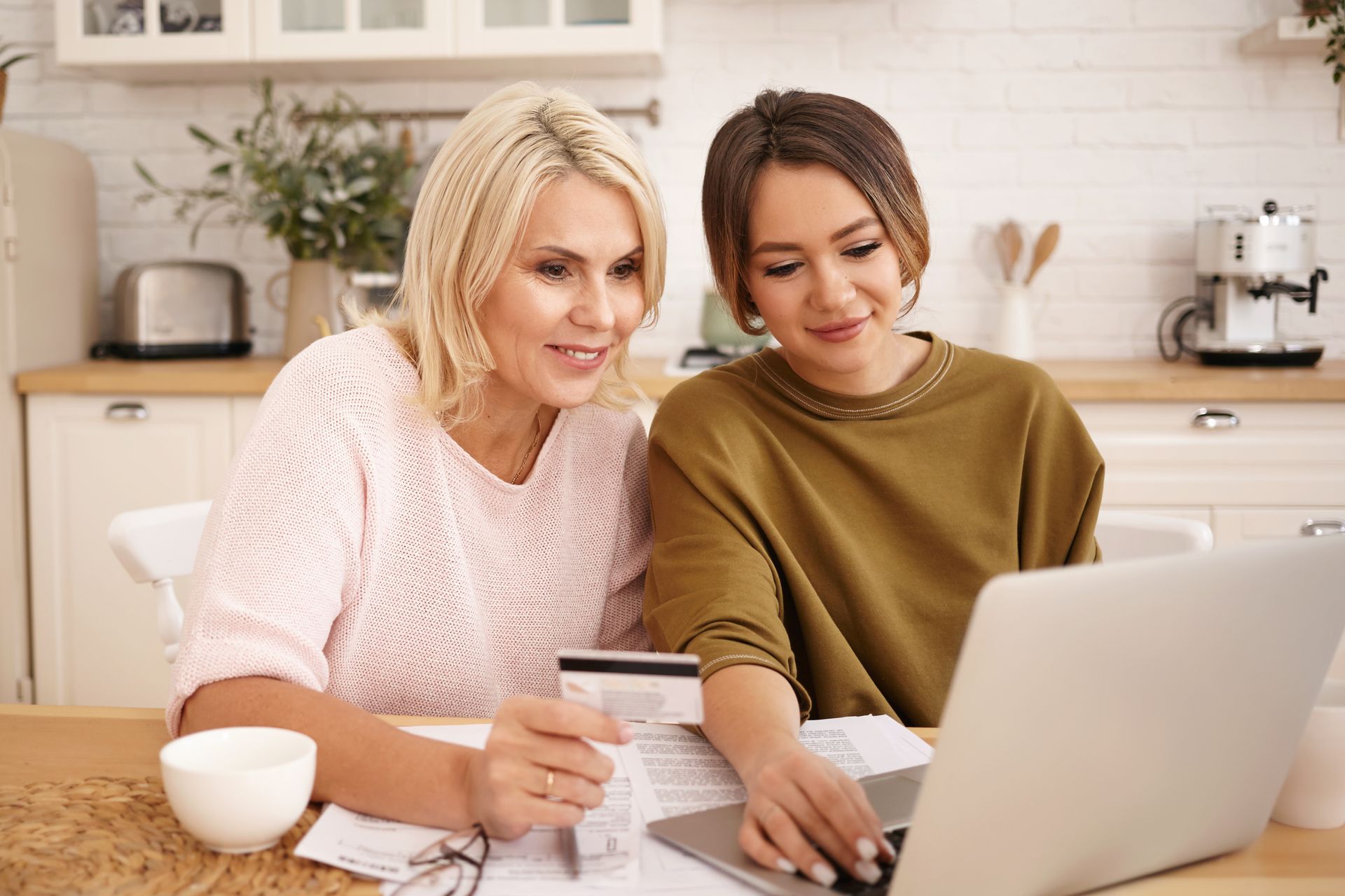 women smiling at computer with payment card