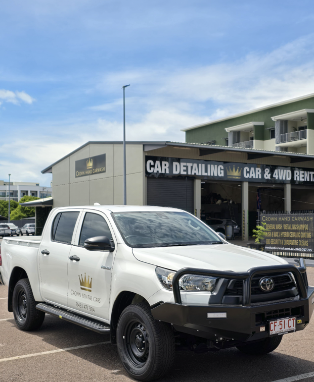White Toyota pickup truck parked in front of a car detailing business with a black bull bar on a sunny day. — Crown Rental Cars in Nightcliff, NT